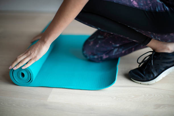 istock Close Up Of Woman Rolling Out Exercise Mat On Floor Before Exercise 1135080722