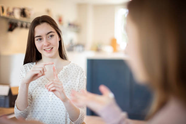 Two Teenage Girls Having Conversation Using Sign Language Two Teenage Girls Having Conversation Using Sign Language american sign language stock pictures, royalty-free photos & images