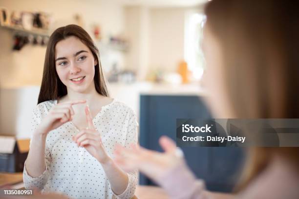 Two Teenage Girls Having Conversation Using Sign Language Stock Photo - Download Image Now