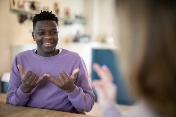 teenage boy and girl having conversation using sign language - sign language imagens e fotografias de stock