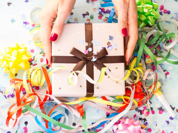istock Gift box in hands above streamers and confetti 1135082457