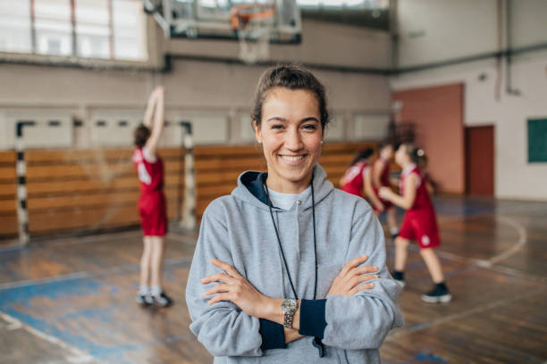 Lady basketball coach on court Group of people, woman basketball coach and teenage girls basketball players. woman coach is standing in front of players. sportsperson stock pictures, royalty-free photos & images