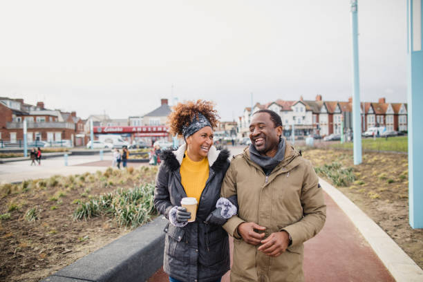 Lunch Break Stroll A couple walking arm-in-arm catching up over a coffee as they walk along a footpath. habitat 67 stock pictures, royalty-free photos & images