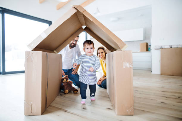 un retrato de la familia joven con una muchacha del niño que se mueve en nuevo hogar. - moving house physical activity moving van box fotografías e imágenes de stock