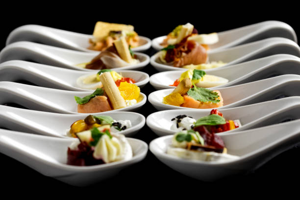 istock Two rows of canapes on white ceramic spoons. Black background. 1135086901