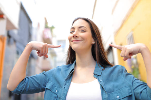 гордая женщина, указывающая на себя на улице - teenage girls cheerful smiling one person стоковые фото и изображения