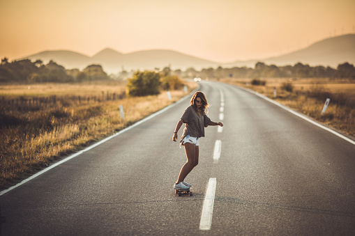 Full length of young woman skateboarding on the road. Copy space.