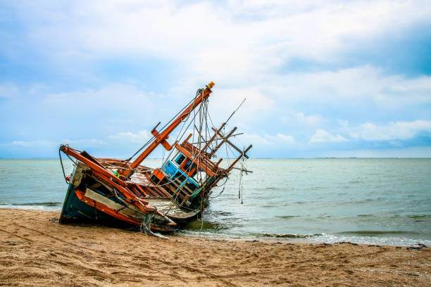 Wrecked fishing boat on the beach Wrecked fishing boat on the beach fishing boat sinking stock pictures, royalty-free photos & images