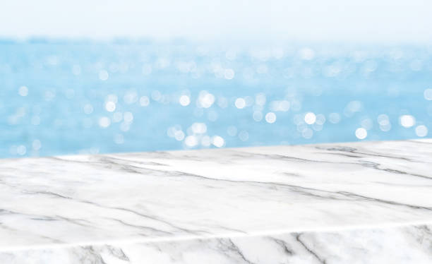 istock Empty glossy white marble table top with blur sky and sea boekh background,banner mock up template for display of product. 1135089158
