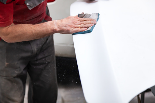 Preparación para la pintura de un elemento de coche utilizando esponja de esmeril por un técnico de servicio de nivelación antes de aplicar una imprimación después de dañar a una parte del cuerpo en un accidente en el taller del vehículo photo