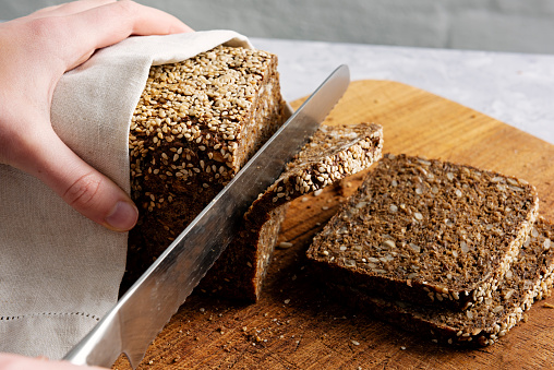 Studio shot of a loaf of rye bread made with organic rye wheat being cut into slices. Colour, horizontal with some copy space.