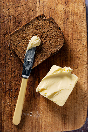 Studio shot of a sliced loaf of rye bread made with organic rye wheat, with a block of butter. Colour, vertical with some copy space, overhead view looking down.