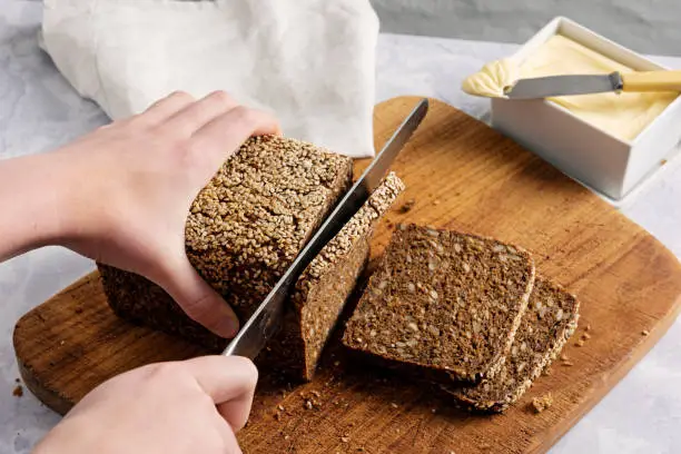 Studio shot of a loaf of rye bread made with organic rye wheat being cut into slices. Colour, horizontal with some copy space.