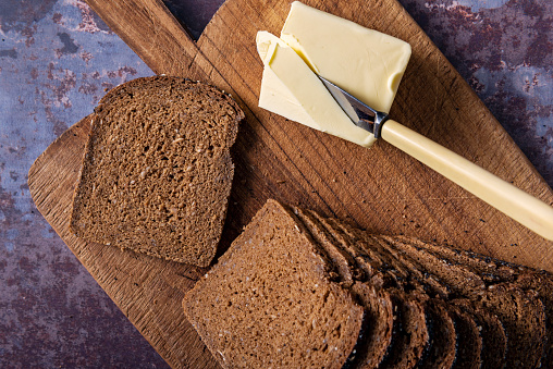 Studio shot of a sliced loaf of rye bread made with organic rye wheat, with a block of butter. Colour, horizontal with some copy space, overhead view looking down.