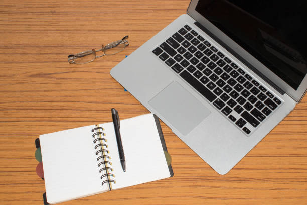 Desk with open notepad, pen, eye glasses, nicely placed on office table. Top view with copy space. Business still life concept with office stuff on table.
