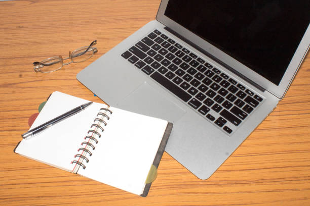 istock Desk with open notepad, pen, eye glasses, nicely placed on office table. Top view with copy space. Business still life concept with office stuff on table. 1135093136