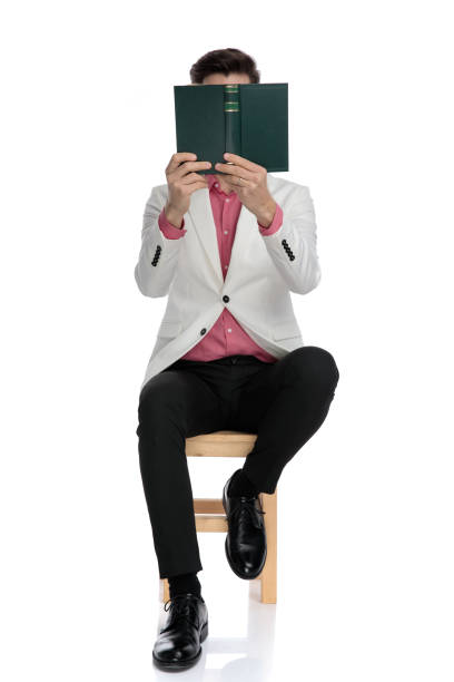 istock young seated elegant man reading with book covering his face 1135095657