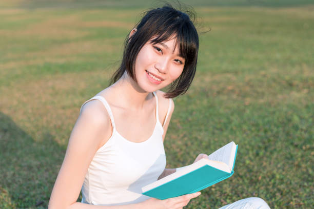 istock young woman reading a book in the park 1135097060
