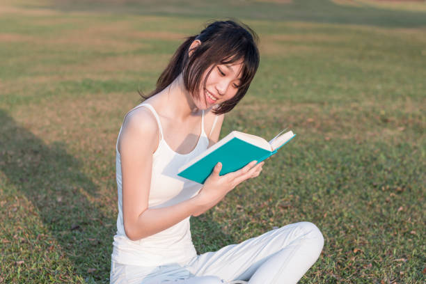 istock young woman reading a book in the park 1135097114