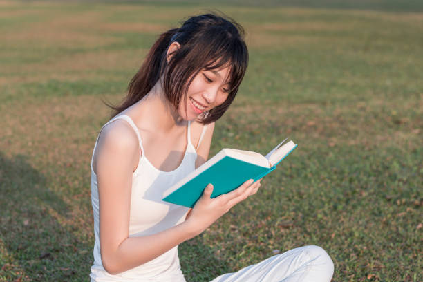 istock young woman reading a book in the park 1135097198