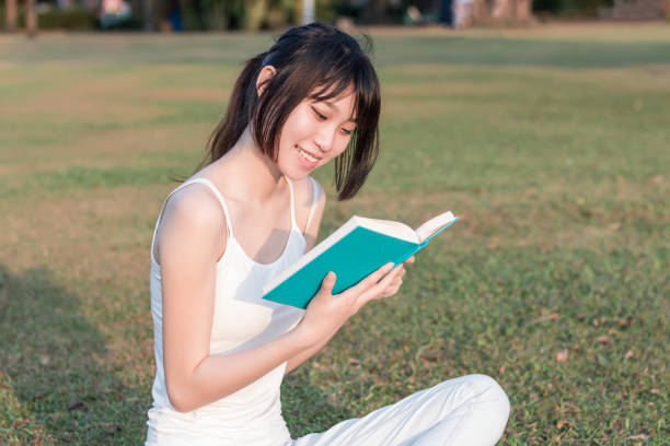istock young woman reading a book in the park 1135097279