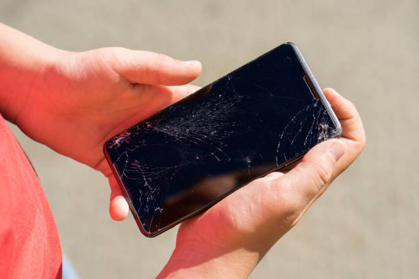 istock teen is holding phone with broken screen after falling down 1135098271