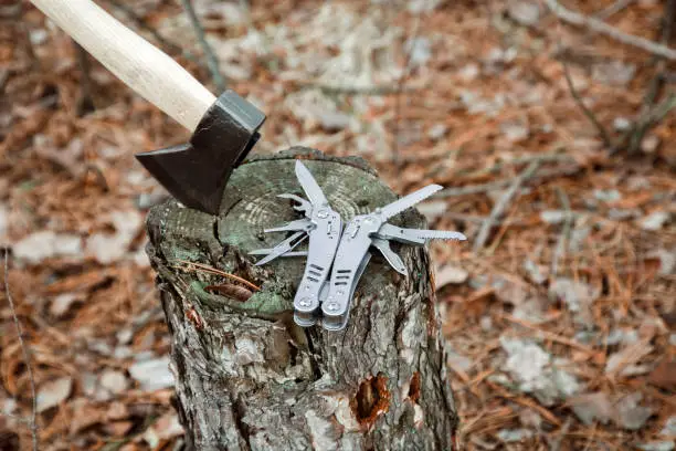 axe, multitool knife on the stump, in the autumn forest