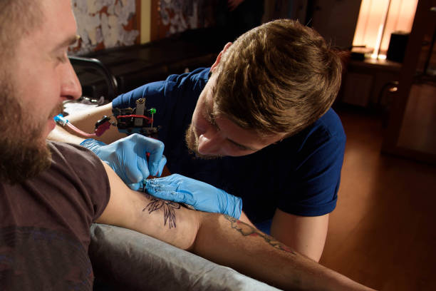 istock Professional tattoo artist makes a tattoo on a man's hand. 1135099994