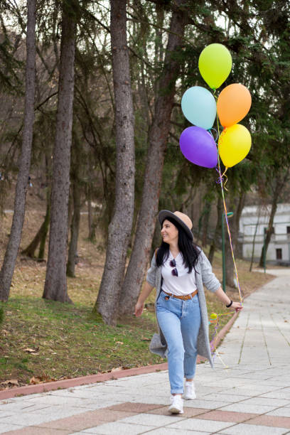 istock Young woman having fun in park with helium balloons 1135100528