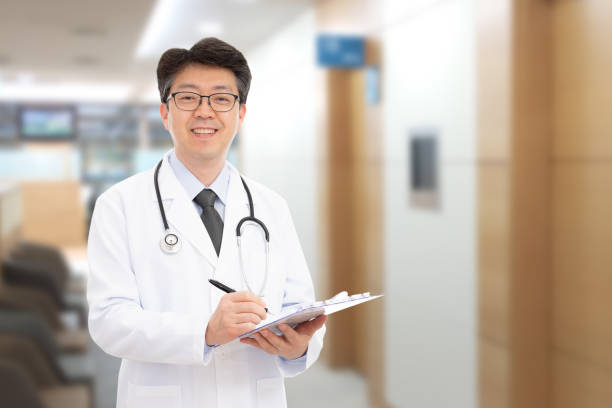 Asian male doctor smiling in the background of the hospital stock photo