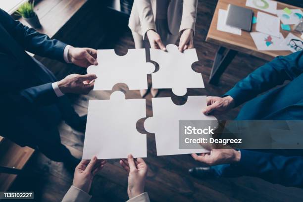 Cropped Top Above High Angle View Of Stylish Elegant Sharks Holding In Hands Fitting Big Large Puzzle Pieces Together Team Building In Loft Industrial Interior Work Place Station Stock Photo - Download Image Now