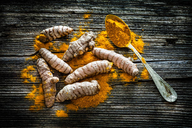 istock Spices: Turmeric roots and powder shot from above on rustic wooden table 1135102394