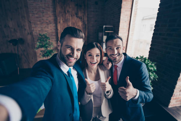 istock Self-portrait of three nice stylish beautiful handsome cheerful optimistic hr managers bankers economists showing thumbup great in loft industrial interior work place station 1135102734