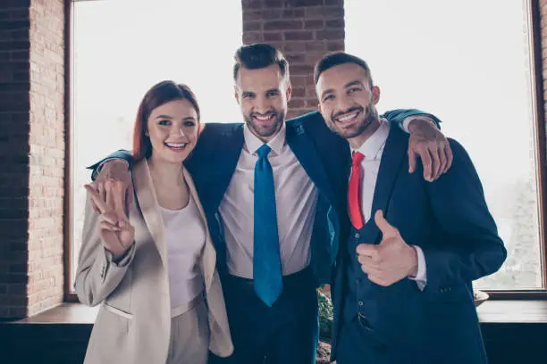 Portrait of three nice elegant stylish beautiful handsome cheerful business sharks showing thumbup v-sign career promotion growth in loft industrial interior work place station.
