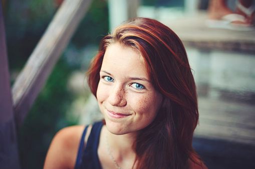 Portrait of a handsome teenager with red dyed hair, blue eyes and braces