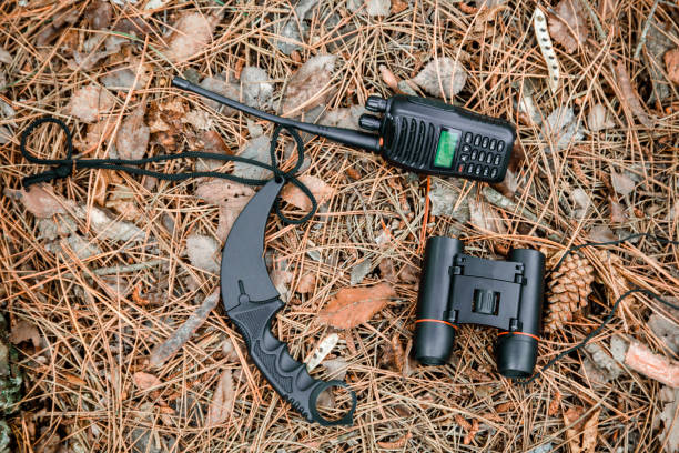 istock binoculars, radio set and karambit knife on the ground covered with pine needles 1135105113