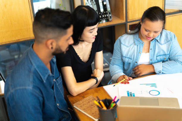 istock Business partners (including Special Needs Woman) discussing new project at modern startup office 1135106358