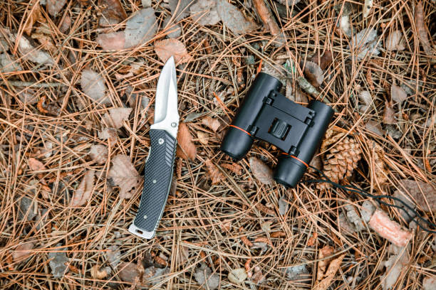 istock binoculars and jackknife on the ground covered with pine needles 1135106444