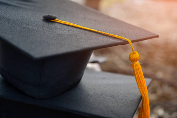 sombrero negro de graduados universitarios - toga fotografías e imágenes de stock