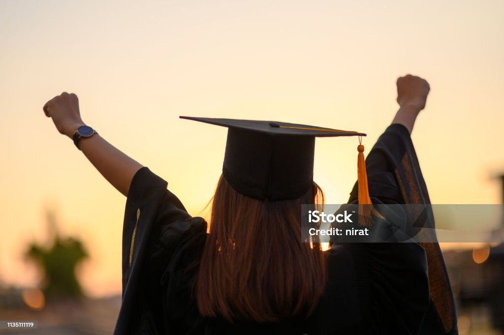 Graduates wear a black dress, black hat at the university level. Graduation Stock Photo