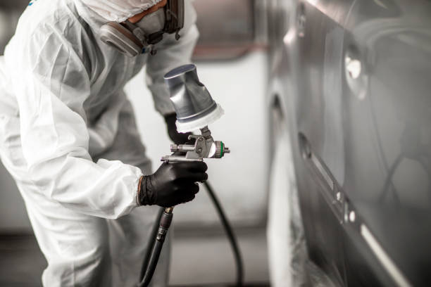 istock Car colorist in white overalls spraying a car segment with paint 1135111782