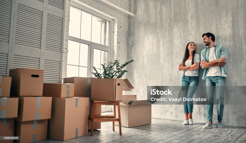 Couple on moving day Couple on moving day. Attractive young woman and handsome bearded man with cardboard moving boxes are happy to move into new home. Moving House Stock Photo