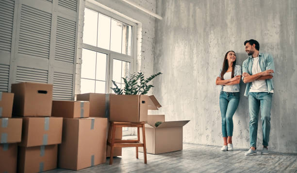 Couple on moving day Couple on moving day. Attractive young woman and handsome bearded man with cardboard moving boxes are happy to move into new home. house key photos stock pictures, royalty-free photos & images