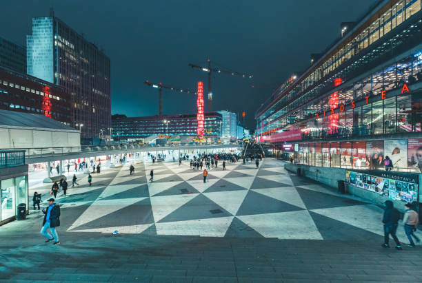 The iconic Kristall obelisk illuminated in the centre of Sergels torg, the modern public square in the heart of Stockholm, overlooking the pedestrianised plaza, traffic roundabout, Kulturhuset, shops and office buildings glowing under the blue dusk sky. ProPhoto RGB profile for maximum color fidelity and gamut.