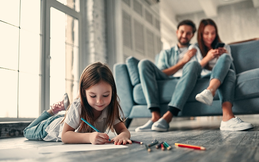 Happy family concept. Handsome bearded man and attractive young woman with little cute daughter are at home together.