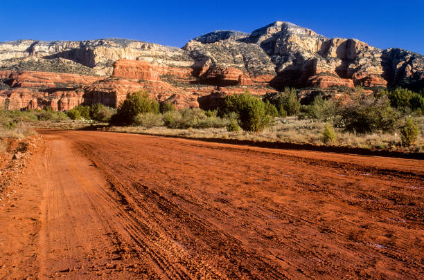 Red canyon road in Sedona, Arizona, U.S.A.  After a rain storm the road looks even more red, than on a dry dusty day.  Bear Mountain in background.  Sunrise photograph(film).