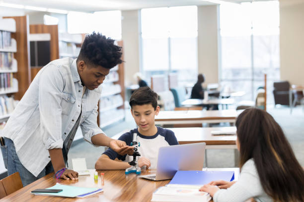 istock Teen boy mentors middle school students in library 1135118077