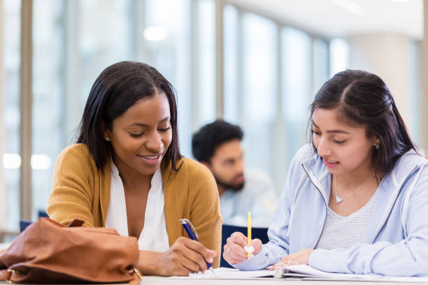 istock Female college friends study together in library 1135118181