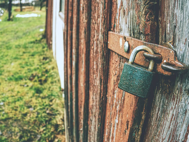 Padlock on wooden gates upholstered with iron. Locked doors