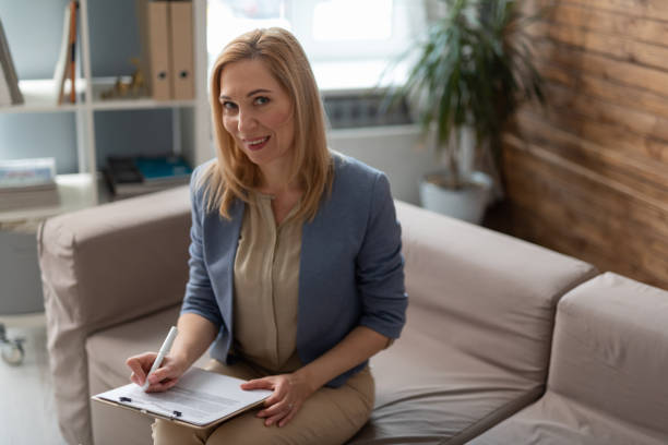 istock Smiling blonde psychologist making notes on clipboard in cabinet 1135118409